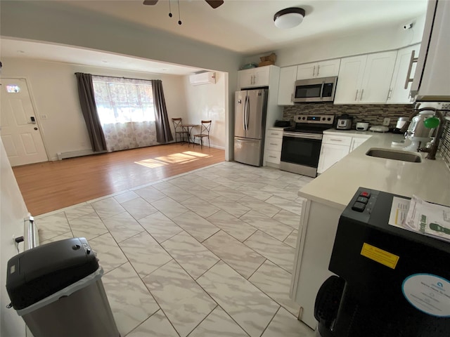 kitchen with sink, white cabinets, decorative backsplash, stainless steel appliances, and a wall unit AC