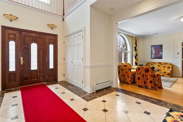 foyer entrance featuring a towering ceiling, ornamental molding, and a baseboard radiator