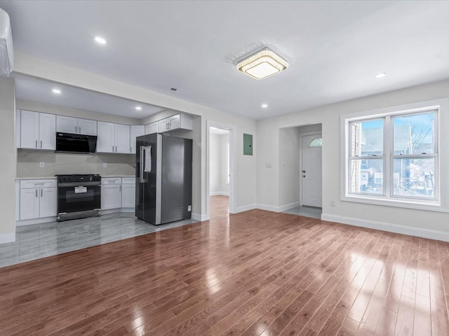 kitchen featuring stainless steel refrigerator with ice dispenser, white cabinets, hardwood / wood-style floors, and stove