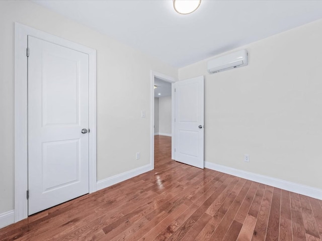 unfurnished bedroom with hardwood / wood-style flooring and a wall mounted air conditioner