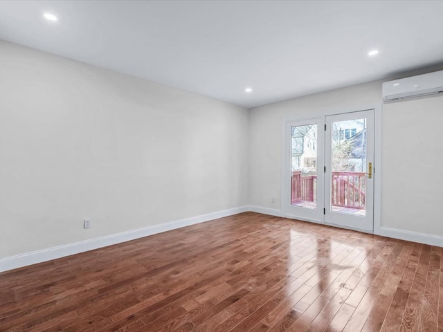 spare room with wood-type flooring and an AC wall unit