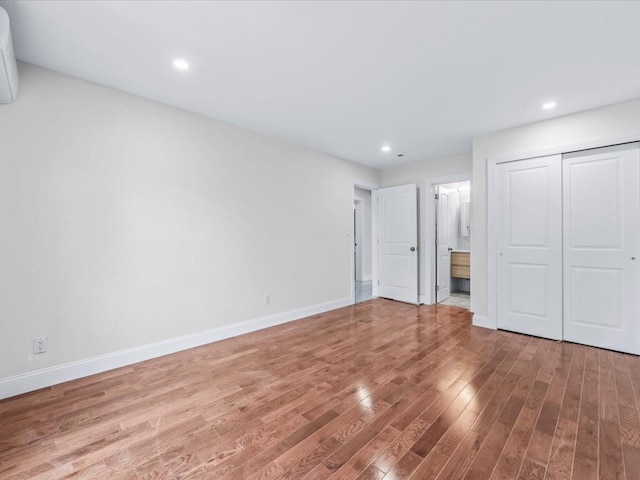 unfurnished bedroom featuring ensuite bath, wood-type flooring, and a closet