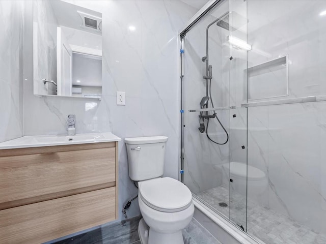 bathroom featuring a shower with door, vanity, and toilet