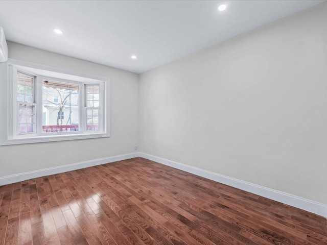 spare room featuring a wall unit AC and dark hardwood / wood-style flooring