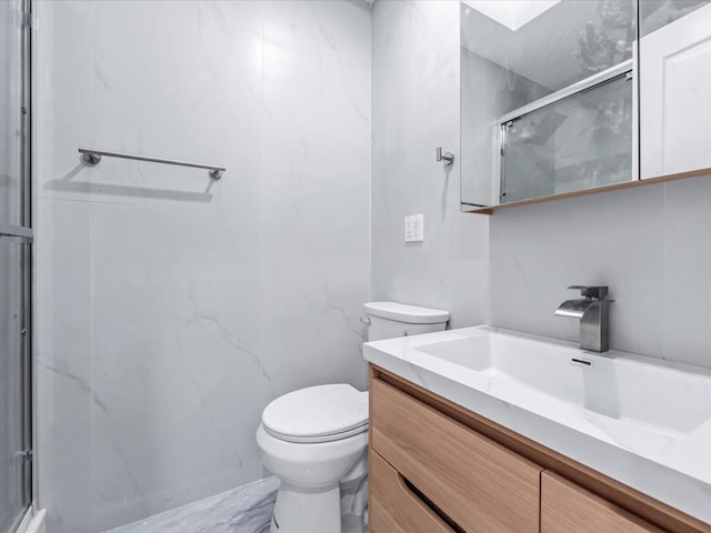 bathroom featuring vanity, a shower with shower door, and toilet