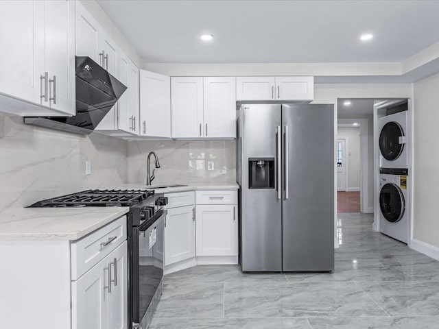 kitchen featuring appliances with stainless steel finishes, light stone countertops, stacked washer / drying machine, and white cabinets