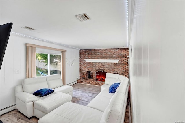 living room with a brick fireplace, baseboard heating, and light hardwood / wood-style flooring