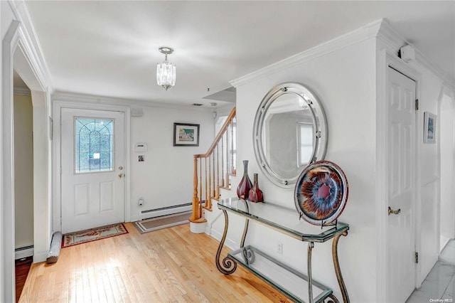 entryway with baseboard heating, ornamental molding, an inviting chandelier, and light wood-type flooring