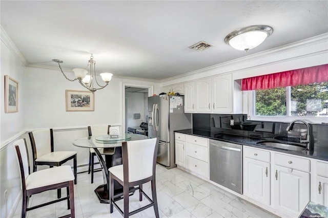 kitchen featuring appliances with stainless steel finishes, decorative light fixtures, white cabinetry, sink, and ornamental molding