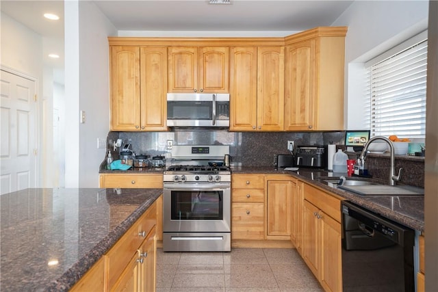 kitchen with appliances with stainless steel finishes, tasteful backsplash, sink, dark stone countertops, and light brown cabinets