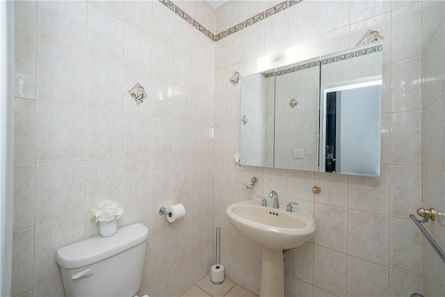 bathroom featuring toilet, sink, and tile walls