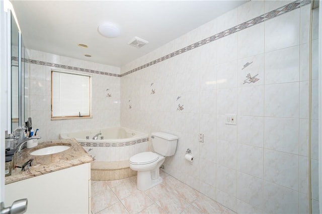 bathroom with tile walls, tile patterned flooring, vanity, a relaxing tiled tub, and toilet