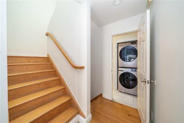 laundry area featuring stacked washer and clothes dryer and light hardwood / wood-style floors