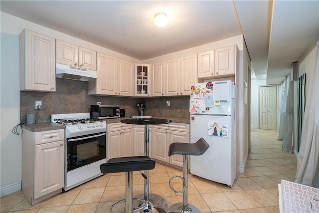 kitchen featuring white cabinetry, sink, backsplash, light tile patterned floors, and white appliances