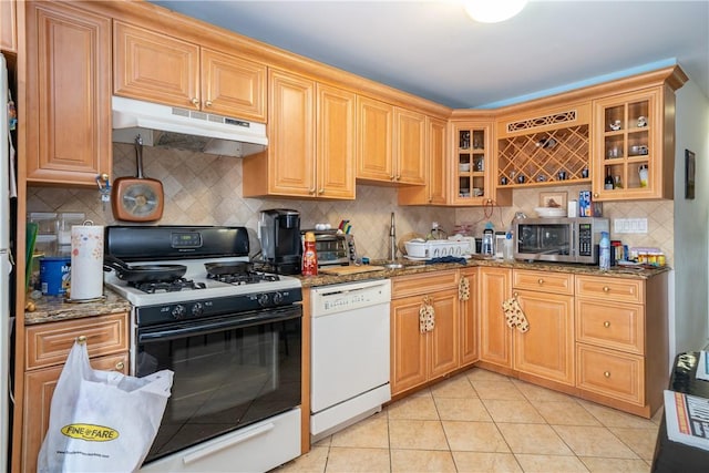 kitchen with sink, stone countertops, light tile patterned floors, white appliances, and backsplash