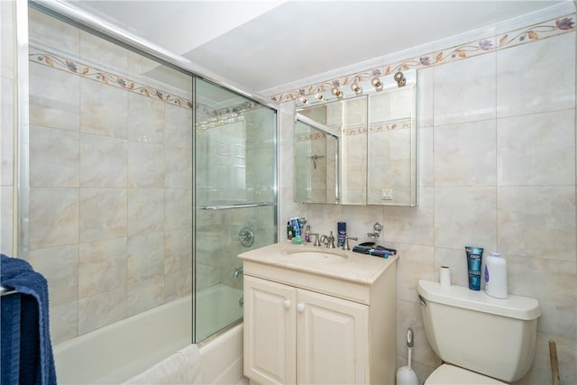 full bathroom with vanity, combined bath / shower with glass door, tile walls, and toilet