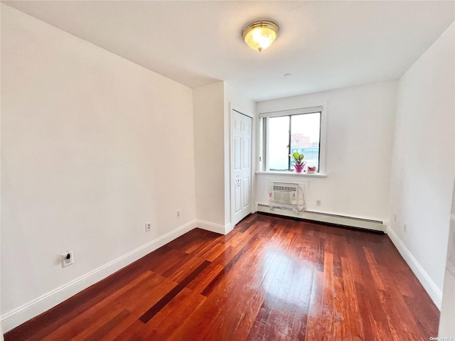 spare room featuring baseboard heating, dark hardwood / wood-style flooring, and a wall mounted AC