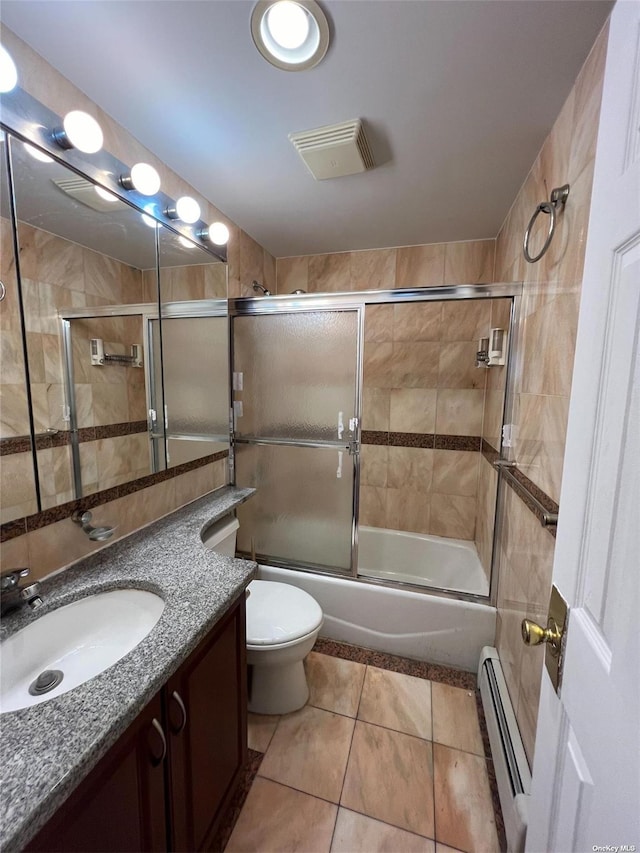 full bathroom featuring combined bath / shower with glass door, baseboard heating, tile patterned flooring, vanity, and toilet