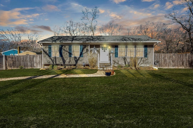 single story home with entry steps, fence, and a lawn