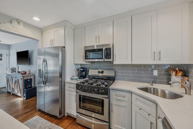 kitchen featuring dark wood-type flooring, sink, white cabinetry, tasteful backsplash, and appliances with stainless steel finishes