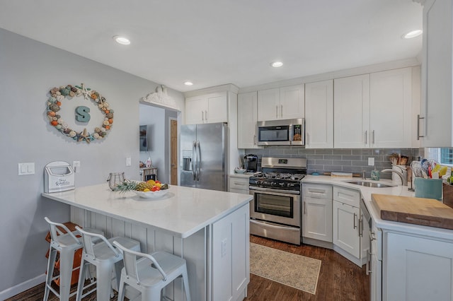 kitchen featuring a breakfast bar, sink, white cabinetry, tasteful backsplash, and appliances with stainless steel finishes