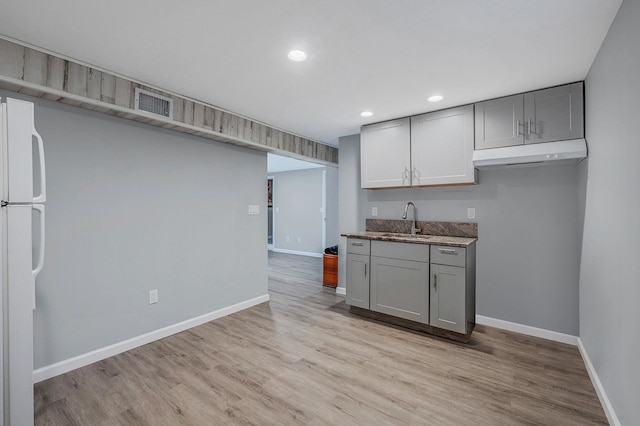 kitchen featuring light wood-type flooring, sink, white fridge, and gray cabinetry