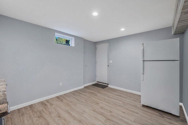 basement with white fridge and light wood-type flooring