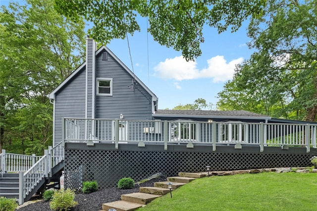 rear view of house with a wooden deck and a yard