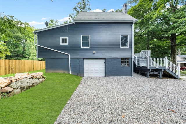 back of house featuring a wooden deck, a garage, and a lawn