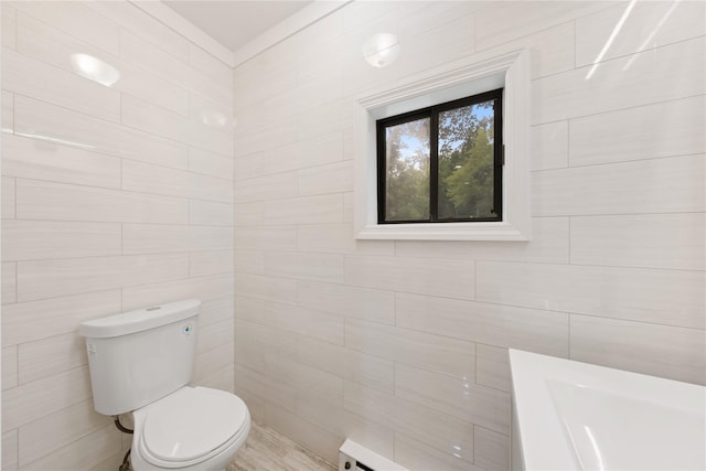 bathroom featuring toilet, tile walls, and a baseboard heating unit