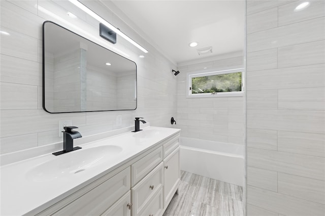 bathroom featuring tile walls, vanity, and tiled shower / bath