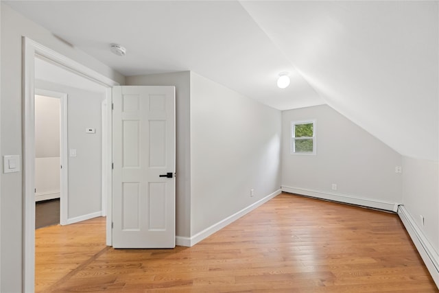 additional living space featuring a baseboard radiator, lofted ceiling, and light hardwood / wood-style floors