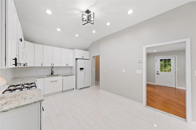 kitchen with sink, white appliances, light stone countertops, white cabinets, and decorative backsplash