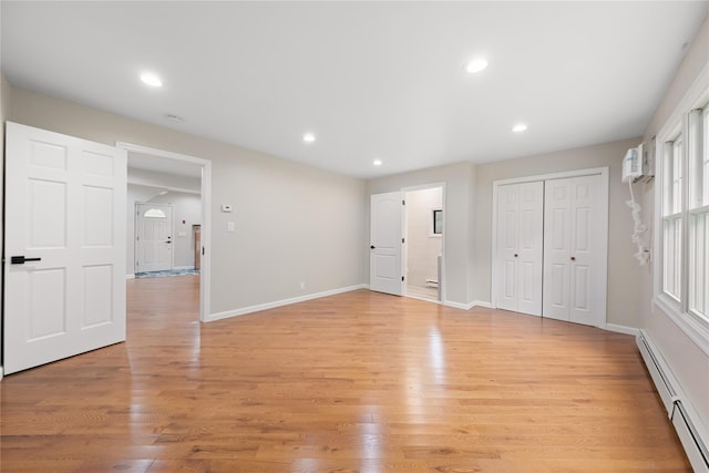 unfurnished bedroom featuring light hardwood / wood-style flooring, a baseboard radiator, a closet, and ensuite bathroom