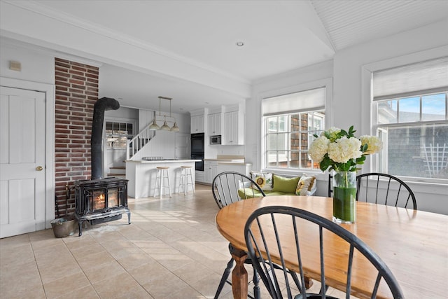 tiled dining area with crown molding, plenty of natural light, and a wood stove