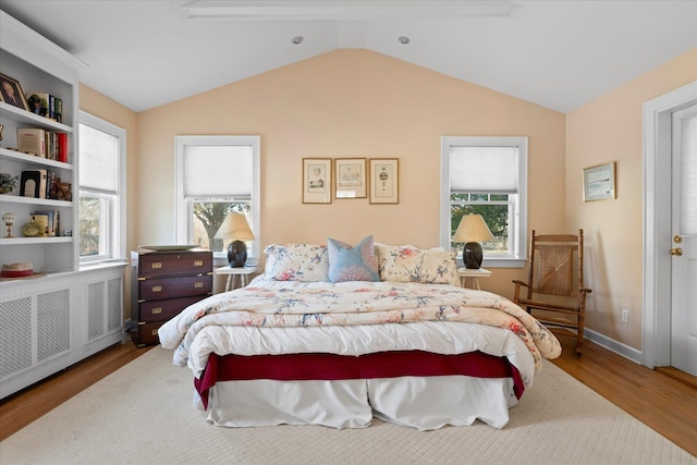 bedroom with multiple windows, radiator, wood-type flooring, and lofted ceiling