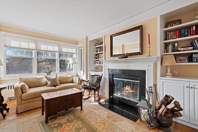 living room with ornamental molding, radiator, light hardwood / wood-style flooring, and built in shelves