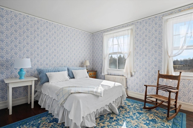 bedroom with radiator heating unit and dark hardwood / wood-style flooring