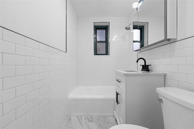 full bathroom with tile walls, vanity, tiled shower / bath, and toilet