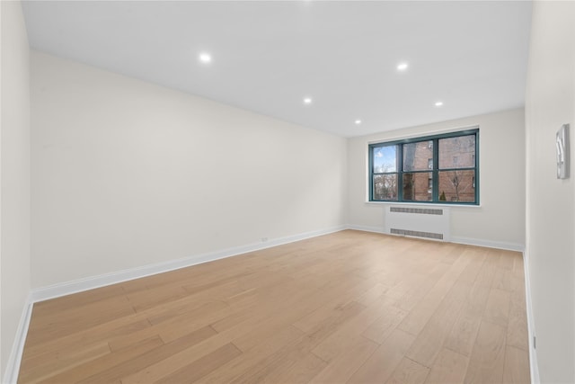 unfurnished room featuring radiator and light hardwood / wood-style flooring