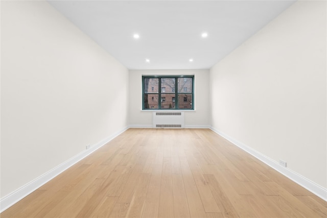 spare room with radiator and light hardwood / wood-style floors