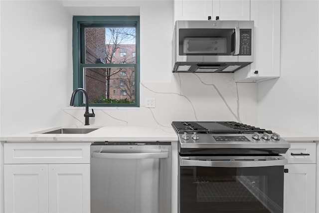 kitchen featuring sink, decorative backsplash, white cabinets, and appliances with stainless steel finishes