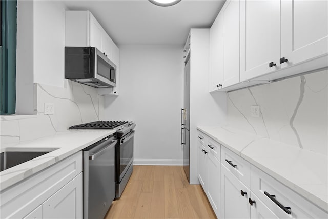 kitchen with white cabinetry, light stone countertops, decorative backsplash, and stainless steel appliances