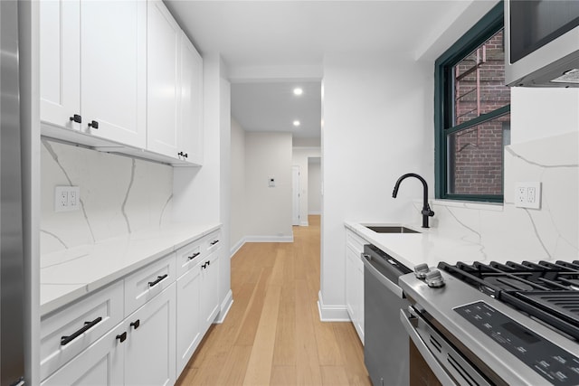 kitchen with stainless steel appliances, white cabinets, light hardwood / wood-style floors, and decorative backsplash