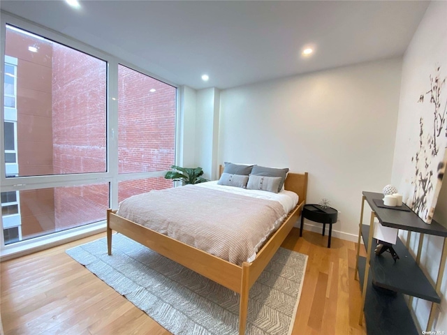 bedroom featuring a wall of windows and light hardwood / wood-style floors