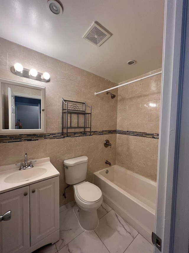 full bathroom with toilet, tile walls, vanity, tiled shower / bath combo, and backsplash