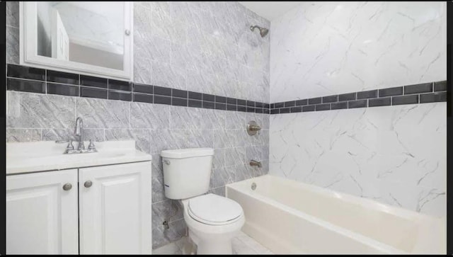 full bathroom featuring tiled shower / bath, vanity, toilet, and tile walls