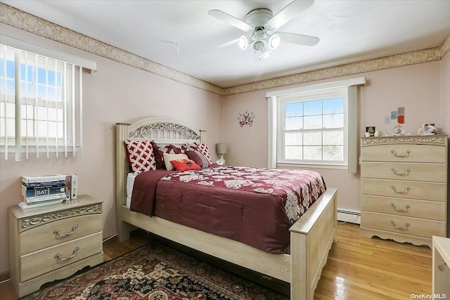 bedroom with light hardwood / wood-style flooring, ceiling fan, and baseboard heating