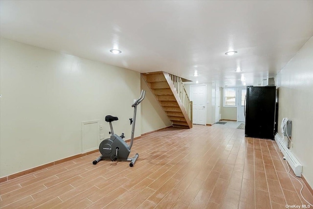 exercise room with heating unit, light hardwood / wood-style flooring, and a baseboard heating unit