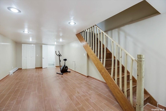 exercise area with a baseboard radiator and hardwood / wood-style floors